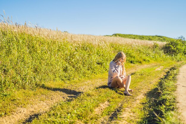 Mujer hermosa joven en el paisaje otoñal con flores secas, espigas de trigo. Moda otoño, invierno. Otoño soleado, suéter acogedor de otoño. foto de moda