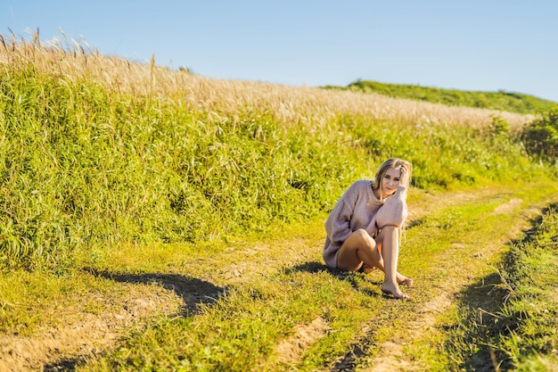 Mujer hermosa joven en el paisaje de otoño con flores secas espigas de trigo Moda otoño invierno Otoño soleado Acogedor suéter de otoño foto de moda