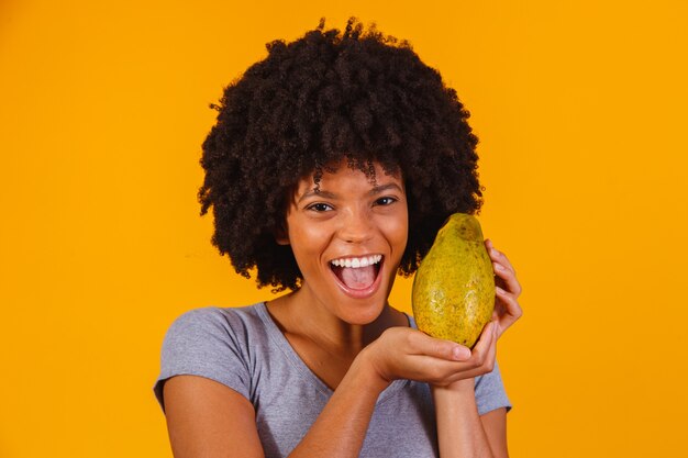 Mujer hermosa joven con papaya en amarillo