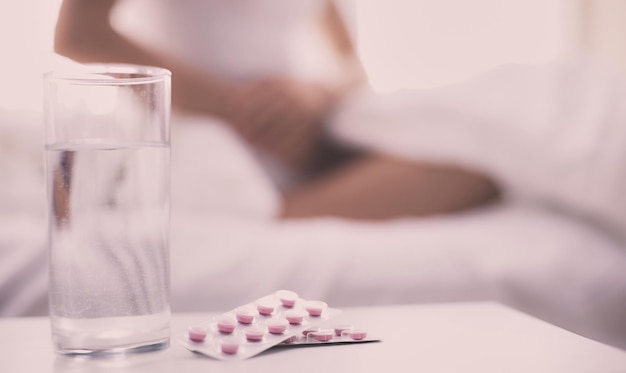 Mujer hermosa joven con pastillas acostada en la cama en el dormitorio