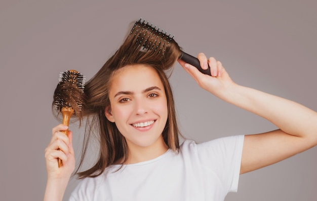 Mujer hermosa joven peinando el cabello castaño cuidado del cabello hermosa mujer morena cepillarse el cabello con h