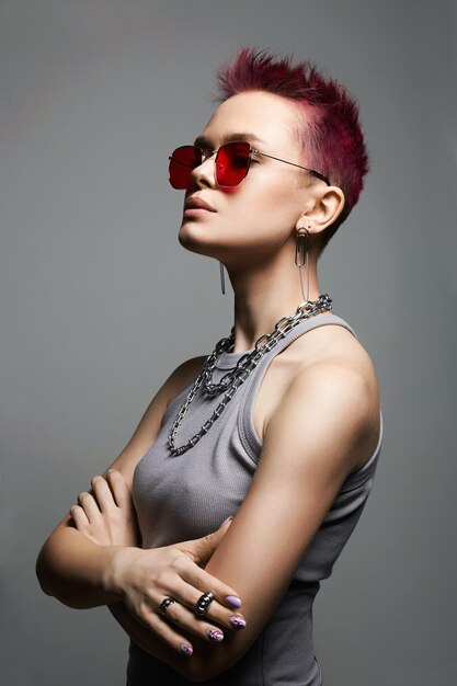 Mujer hermosa joven con pelo corto pintado y un collar de cadena en cristal rojo