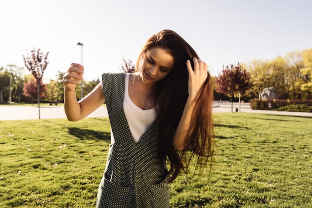 Mujer hermosa joven con el pelo largo está caminando en el parque, disfrutando de la naturaleza