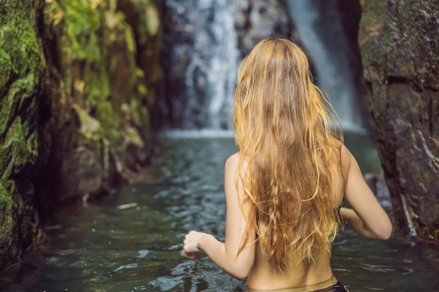 Mujer hermosa joven de pie en el agua en la cascada