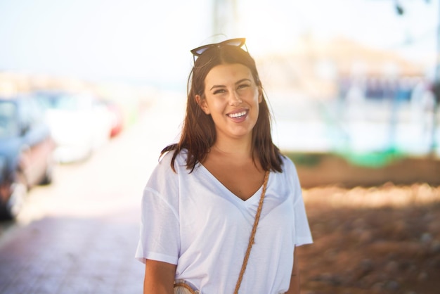 Mujer hermosa joven de pie en la calle sonriendo