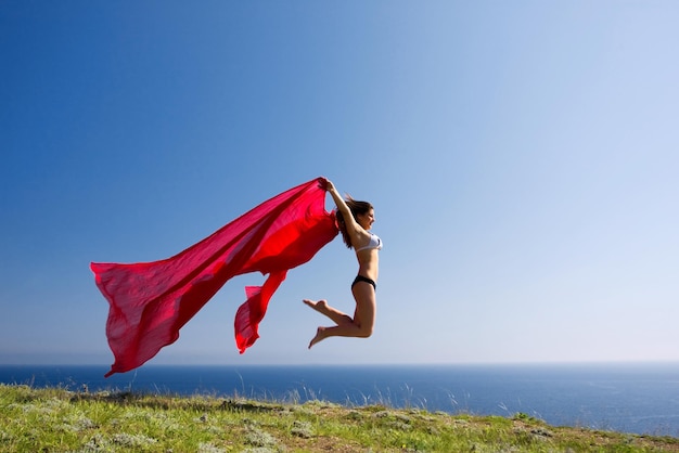 mujer hermosa joven en la playa con material rojo