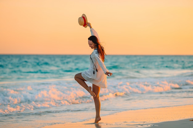 Foto mujer hermosa joven en la playa tropical en puesta de sol.