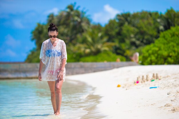 Mujer hermosa joven en la playa durante vacaciones tropicales