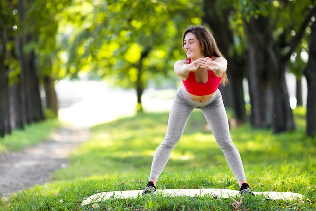 Mujer hermosa joven practicando yoga en el parque verde
