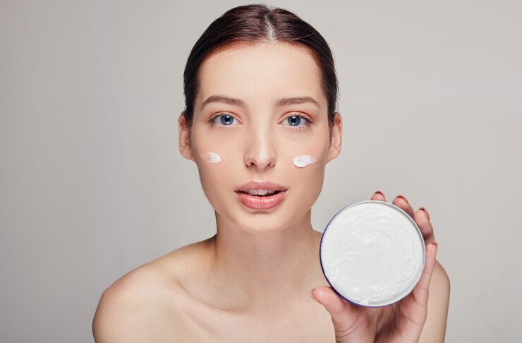 Foto mujer hermosa joven que aplica la crema hidratante en su cara. foto de mujer joven con piel perfecta.