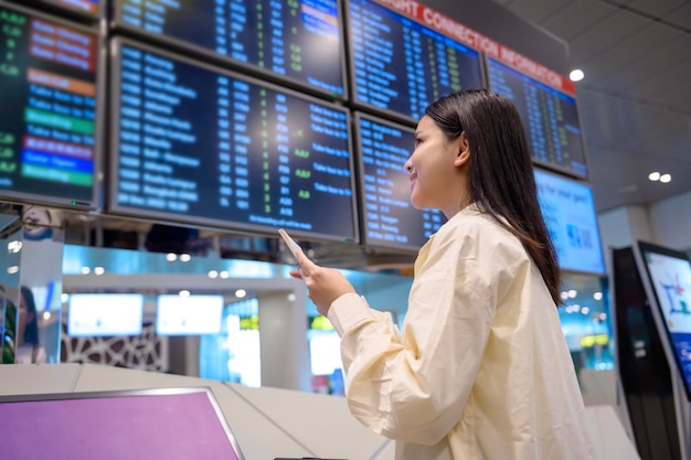 Una mujer hermosa joven que camina con la facturación de la maleta en el aeropuerto internacional