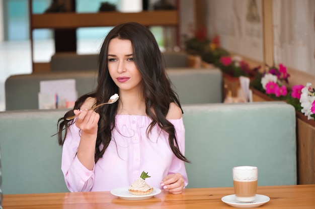 Mujer hermosa joven que come un postre en un café