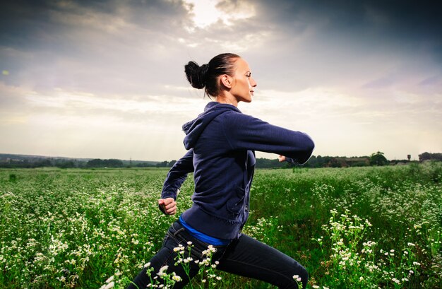 Mujer hermosa joven que hace yoga en un prado