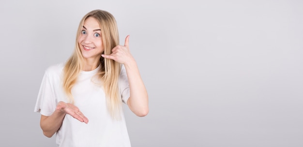 Mujer hermosa joven que sonríe haciendo gesto del teléfono con la mano y los dedos como hablar por teléfono con copyspace