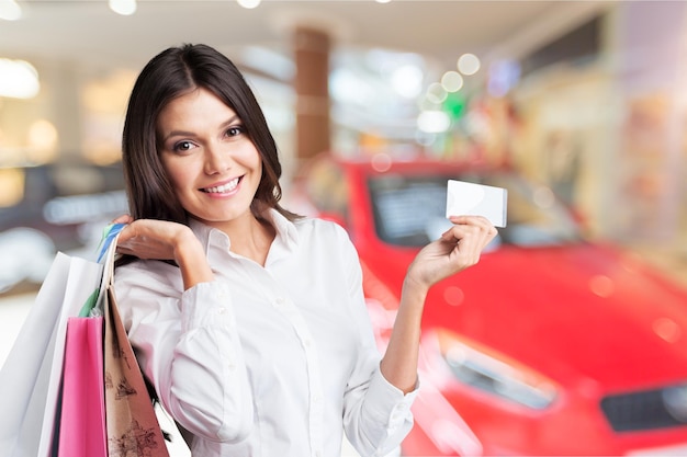 Mujer hermosa joven que sostiene bolsos de compras y una tarjeta de crédito