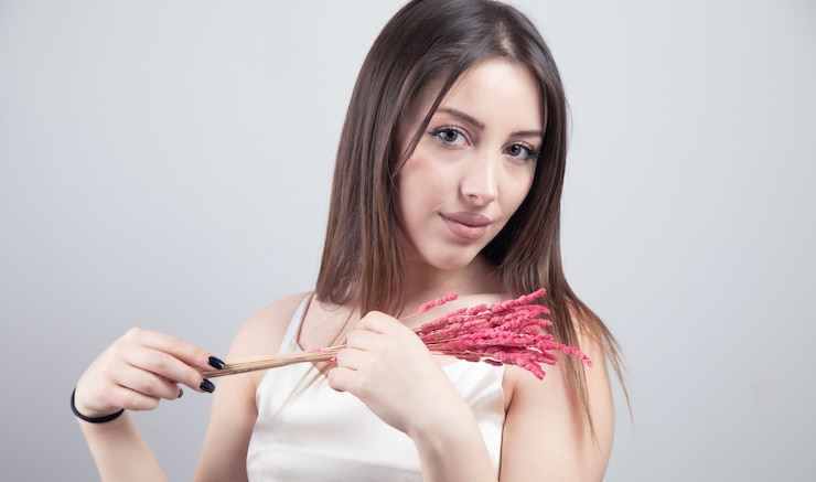 Foto mujer hermosa joven que sostiene la hierba rosada.