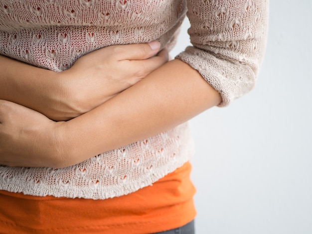 Foto mujer hermosa joven que tiene dolor de estómago doloroso. gastritis crónica. concepto de hinchazón del abdomen.