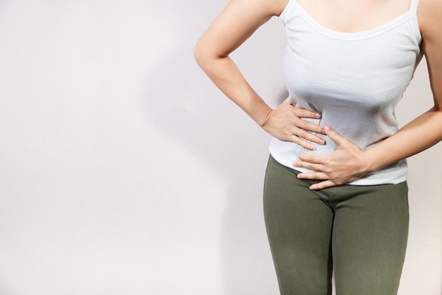 Mujer hermosa joven que tiene dolor de estómago doloroso.