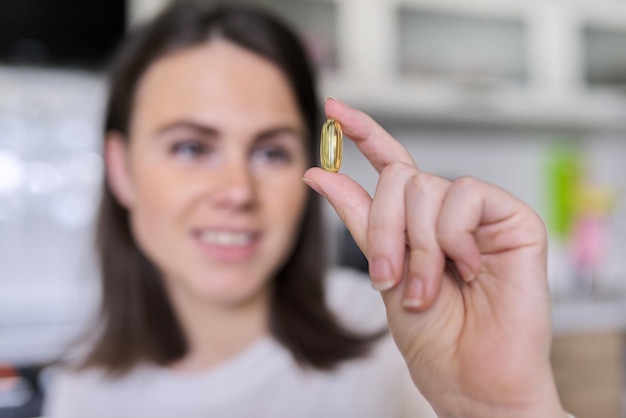 Mujer hermosa joven que toma la vitamina de la píldora con aceite de hígado de bacalao, antioxidante, vitamina a, d, e, aceite de pescado, omega-3