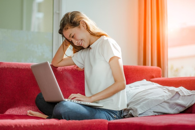 Mujer hermosa joven que usa una computadora portátil en casa