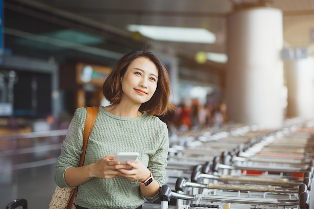 Mujer hermosa joven que usa el teléfono en el aeropuerto.