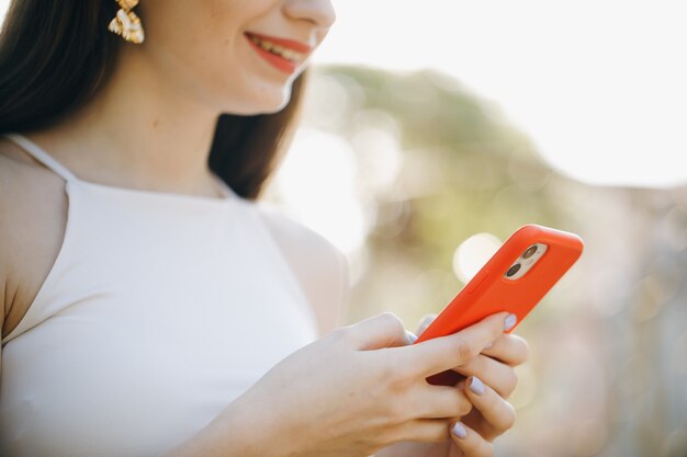 Mujer hermosa joven que usa el teléfono en el parque