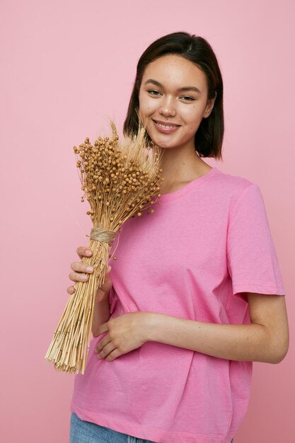 Mujer hermosa joven un ramo de flores secas camiseta rosa fondo aislado