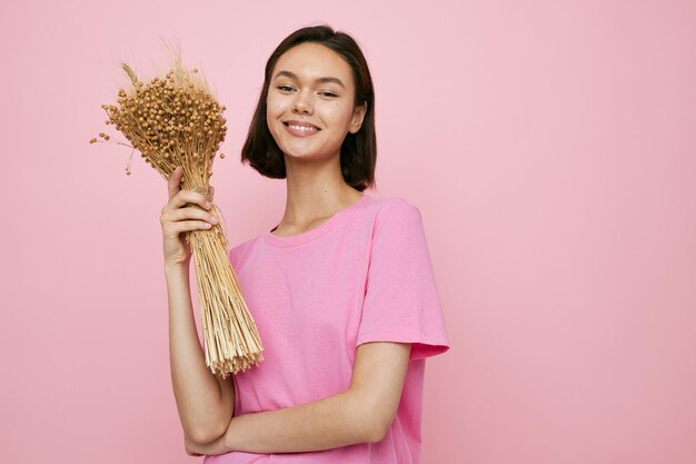 Mujer hermosa joven un ramo de flores secas camiseta rosa fondo aislado