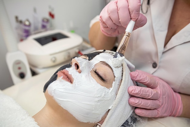 Mujer hermosa joven recibe procedimiento cosmético en la clínica de spa Máscara blanca en la cara para el cuidado de la piel y el cuerpo Estilo de vida