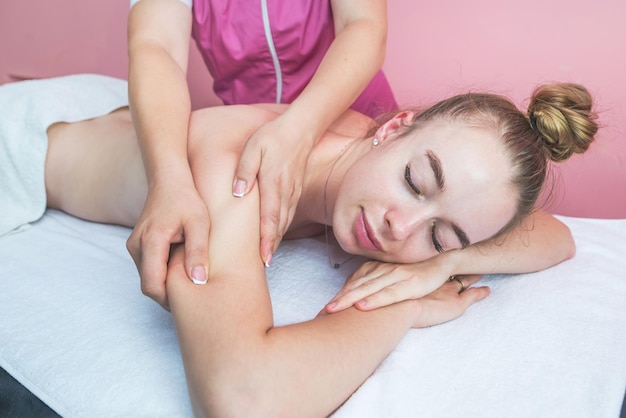 Mujer hermosa joven recibiendo masajes relajantes en la espalda y el cuerpo en un salón de belleza