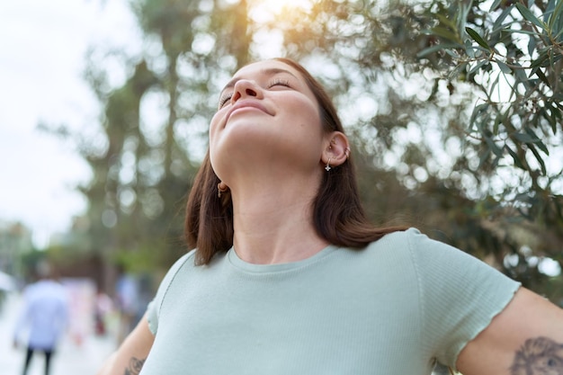 Mujer hermosa joven respirando con los ojos cerrados en el parque