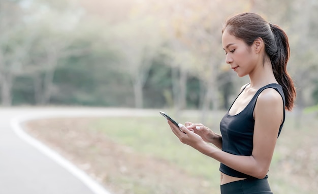 Mujer hermosa joven en ropa deportiva con smartphone