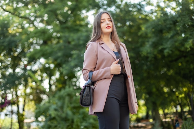 Mujer hermosa joven en ropa de negocios mostrando el pulgar hacia arriba en el parque