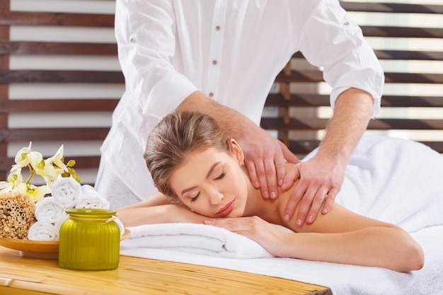 Foto mujer hermosa, joven y saludable en el salón de spa. tratamiento de masaje