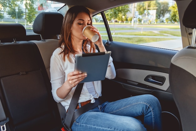 Mujer hermosa joven sentada en el asiento trasero del coche