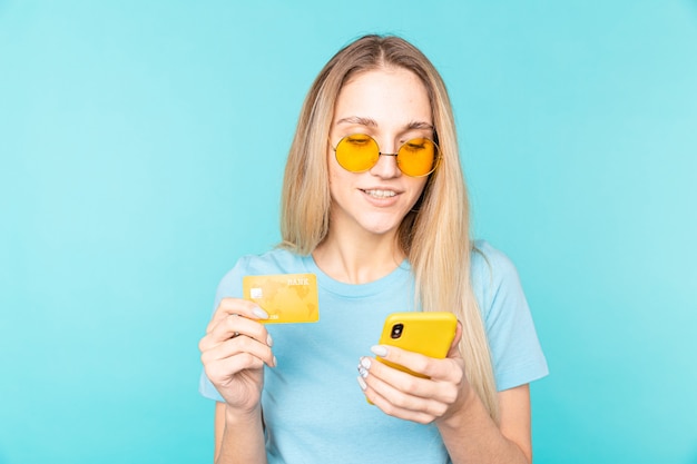 Mujer hermosa joven con smartphone y tarjeta de crédito para compras en línea. Tecnología de pago electrónico.