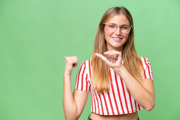 Mujer hermosa joven sobre fondo aislado apuntando hacia un lado para presentar un producto