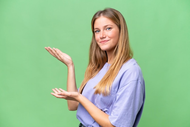 Mujer hermosa joven sobre un fondo aislado extendiendo las manos a un lado para invitar a venir