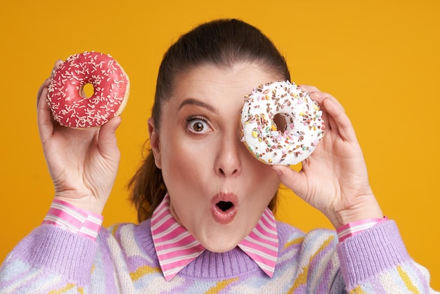 Mujer hermosa joven sobre fondo amarillo con donuts Foto de alta calidad