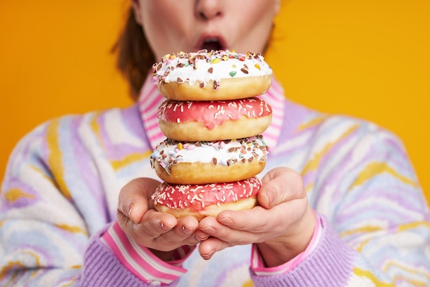 Mujer hermosa joven sobre fondo amarillo con donuts Foto de alta calidad