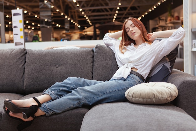 Mujer hermosa joven en un sofá en una tienda de muebles