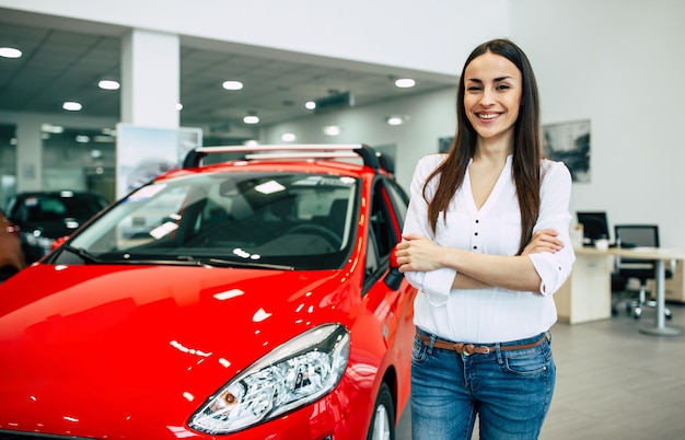 Mujer hermosa joven sonriente en el concesionario Hermosa mujer comprando un auto nuevo para trabajar y viajar en el cliente chica del concesionario