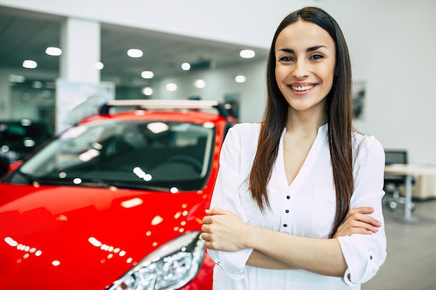 Mujer hermosa joven sonriente en el concesionario Hermosa mujer comprando un auto nuevo para trabajar y viajar en el cliente chica del concesionario