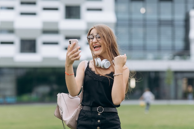 Mujer hermosa joven sorprendida en la calle de la ciudad. Choque por alguna noticia. Ella es hermosa y bonita, joven y divertida. Ella camina por la calle y tiene buen humor