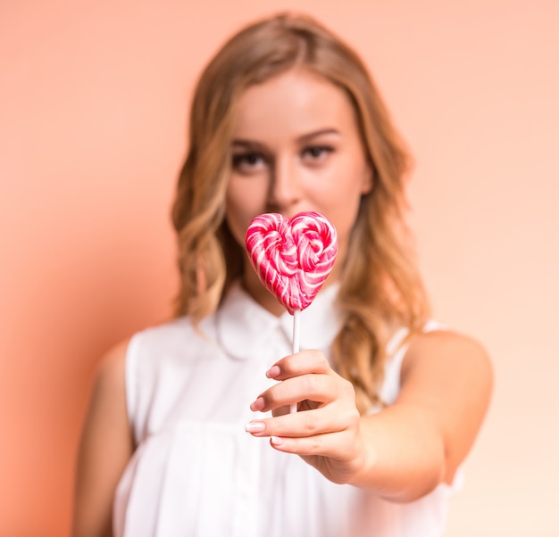 Foto la mujer hermosa joven está sosteniendo un caramelo.