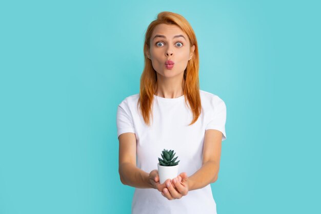 Mujer hermosa joven sosteniendo maceta de cactus sobre fondo azul aislado