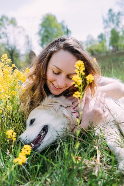 Mujer hermosa joven y su perro golden retriever divirtiéndose en verano