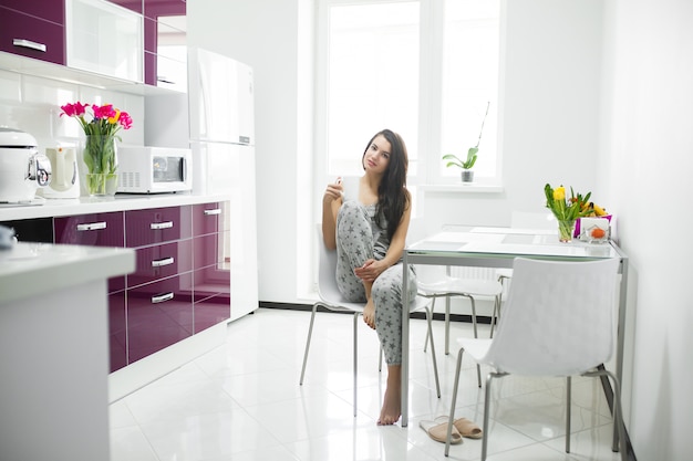 Mujer hermosa joven temprano en la mañana tomando café en la cocina. Mañana fresca Bebida vigorizante. Despierta dama.