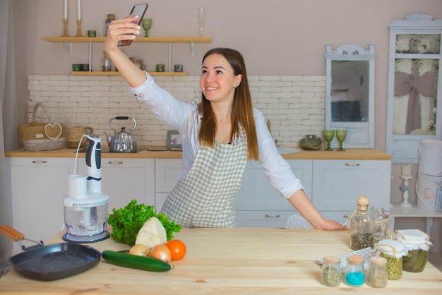 Mujer hermosa joven toma un selfie en la cocina