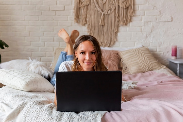 Mujer hermosa joven trabaja para una computadora portátil en la cama.